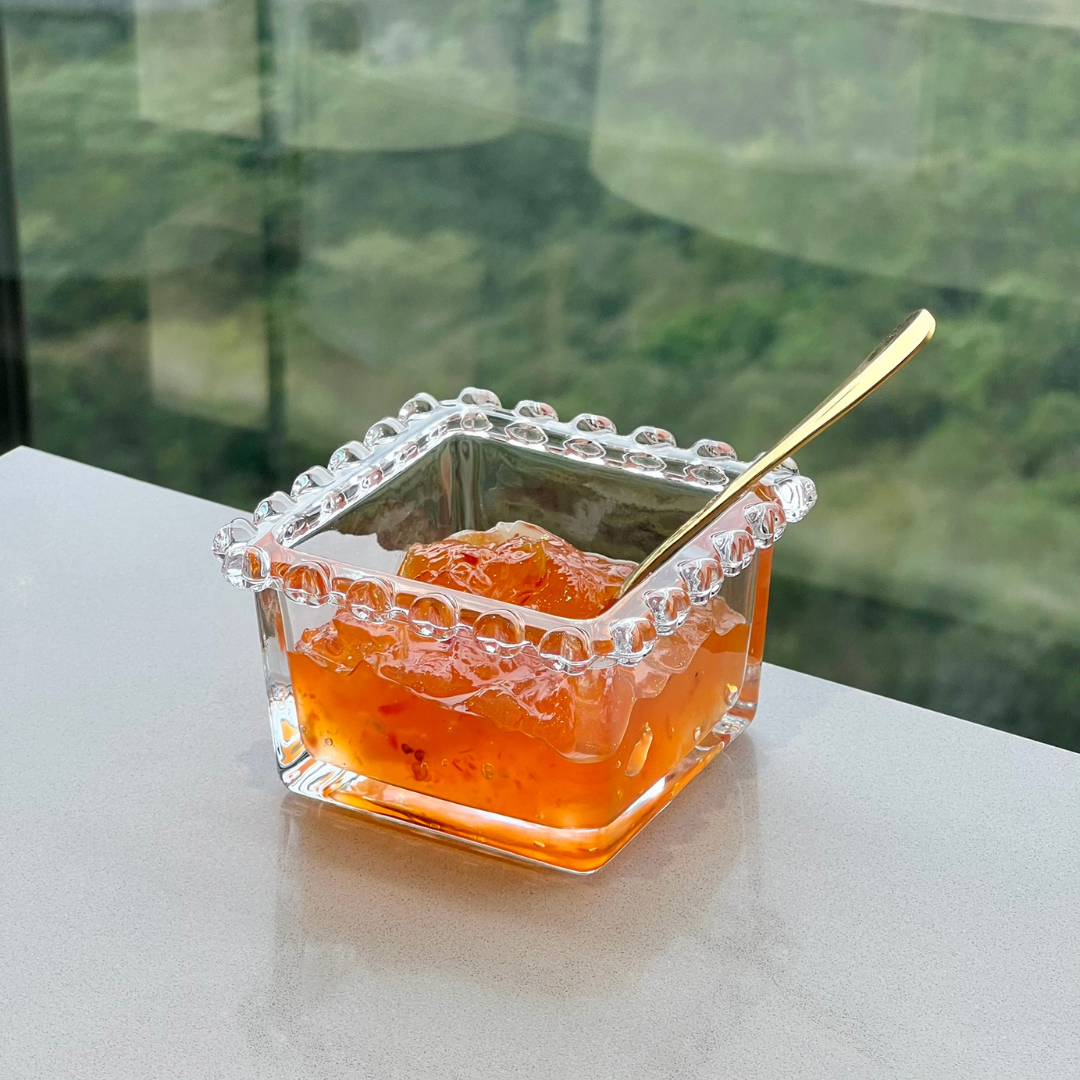 Bowl quadrado cristal com bebida laranja e colher dourada