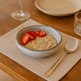 Ramequim branco com flocos servindo mingau de aveia e morango fresco na mesa