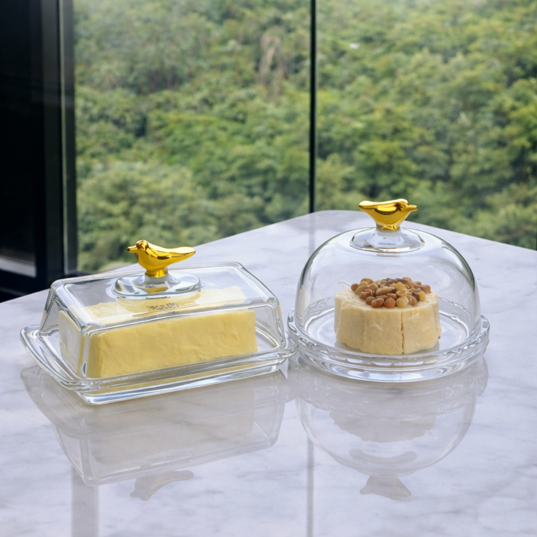 Manteigueira e queijeira Golden Bird em cristal com tampas de vidro e finais dourados sobre mesa