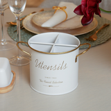 Porta talheres branco com alças douradas em mesa de jantar elegante