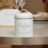 Porta mantimento café metal off white com alça dourada em mesa de jantar