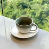 xícara de café cerâmica ombre verde e branco com pires em bancada clara