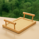 Bandeja de bambu com trama em cortiça sobre superfície bege, com fundo verde de floresta ao fundo.