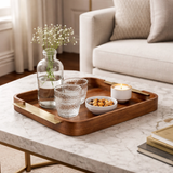 Bandeja marrom grande sobre mesa de centro com vaso, copo e vela decorativos