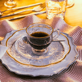 prato de sobremesa e xícara com pires em cima de um jogo americano rosa