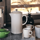 Cafeteira branca com canecas e bowl branco