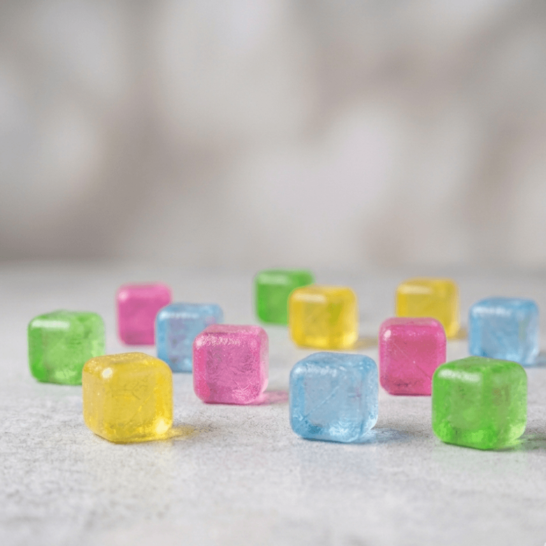 Cubos de gelo reutilizáveis coloridos espalhados em superfície cinza