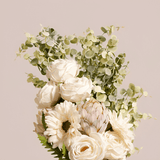 Folhagem verde complementando arranjo floral com rosas e gérberas brancas
