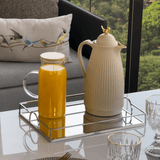 bandeja na mesa posta com jarra de suco de laranja e garrafa bege com passaro dourado