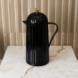 garrafa preta com alça e passaro dourada na tampa