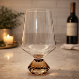 taca para vinho tinto com base diamante ambar em bancada com vela e garrafa