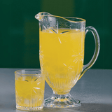 Jarra de cristal com suco de laranja e copo de cristal baixo