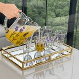 Jarra e seis taças flor de lavanda em cima de uma bandeja dourada e espelhada na mesa