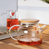 Caneca de vidro com chá quente ao lado de bule na cozinha