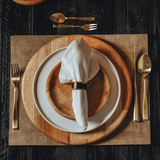 Mesa posta de jantar de madeira natural com talheres dourados e guardanapo branco