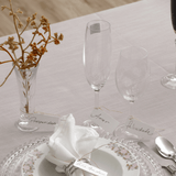 Taças de champanhe e vinho em cristal sobre mesa posta com pratos decorativos e mensagens de felicitações. Ideal para festas, Réveillon ou ocasiões especiais. Combine com taças, jogos de jantar e acessórios de mesa com elegância.