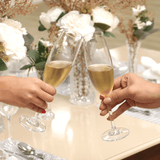 Brinde com taças de champanhe em cristal durante ocasião especial com mesa posta elegante e flores decorativas. Ideal para festas, celebrações e composições com taças, bandejas e jogos de jantar sofisticados.