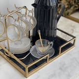 xícara com fio de ouro na borda e vidro canelado em cima de uma bandeja