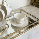 xícara de café branca em uma bandeja de vidro e metal dourado para bancada