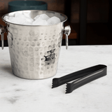 pinça para cubos de gelo ao lado de um balde de gelo com alça em aço inox