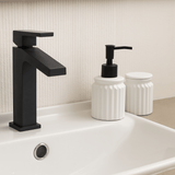 pia de banheiro com torneira preta porta sabonete líquido e porta algodão branco e preto