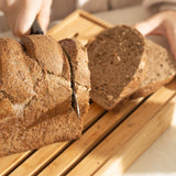 pão integral cortado com faca de serra na tábua de migalheira
