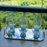 Conjunto de seis tacas transparentes com base esfera azul fume sobre bandeja em varanda