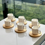 Seis xicaras de cafe em porcelana branca com pires de madeira sobre bancada branca