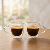 Duas canecas de vidro borossilicato com café quente sobre mesa de madeira