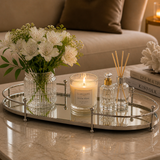 Bandeja oval espelhada com alças em metal decorando mesa lateral com flores e velas