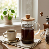 Prensa francesa com café coado em xícara na mesa da cozinha