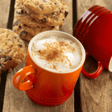 Caneca com cappuccino e chocolate na mesa de café da manhã