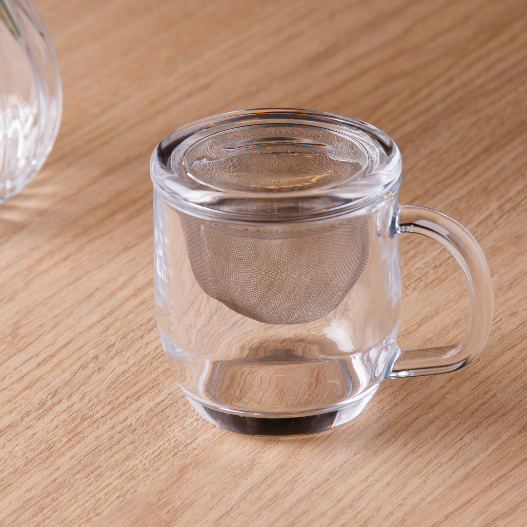 Caneca vidro com difusor e tampa em vidro borosilicato sobre superfície de madeira