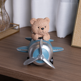 Detalhe da hélice prateada e fuselagem azul com urso sentado