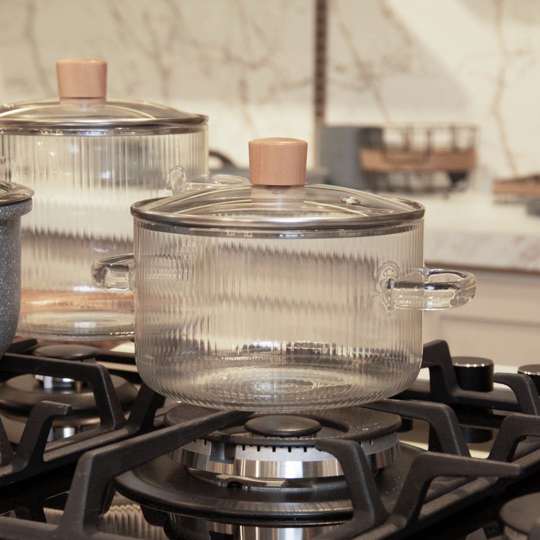 Panela caçarola transparente com alças de metal em fogão aceso
