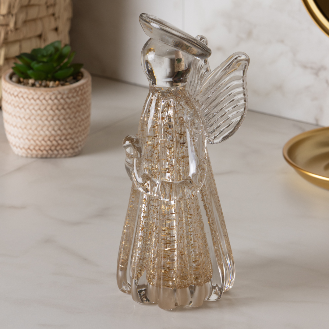 Escultura anjo vidro dourado em ambiente decorativo com plantas