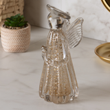 Escultura anjo vidro dourado em ambiente decorativo com plantas
