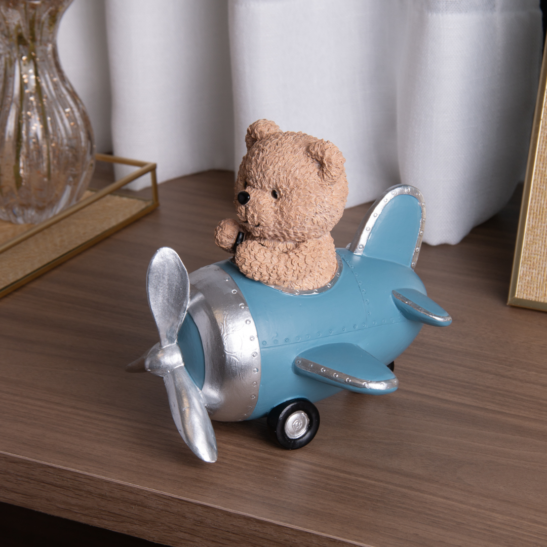 Urso teddy marrom em avião azul decorativo sobre mesa de madeira