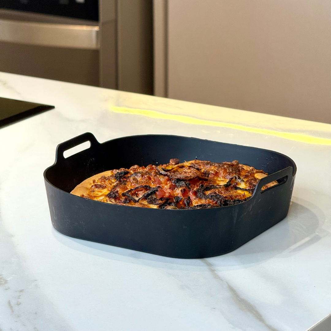 Forma silicone air fryer com frango assado dourado em bancada branca
