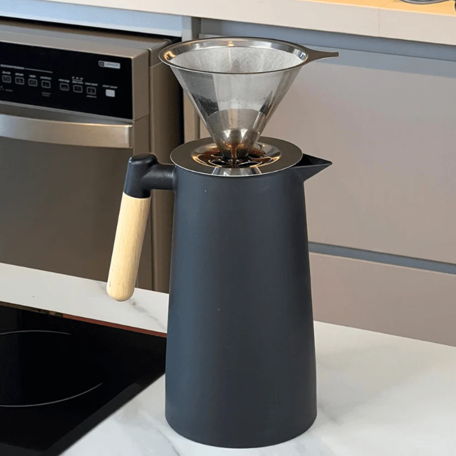 Kit completo café com jarra preta e coador metálico em uso na cozinha