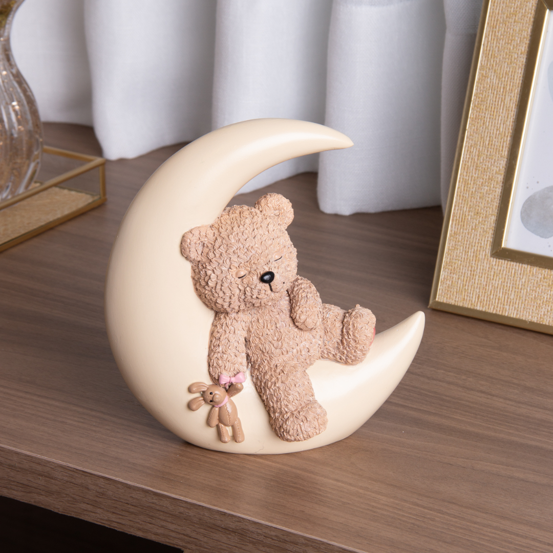 Urso de pelúcia bege sentado em lua de resina decorativa