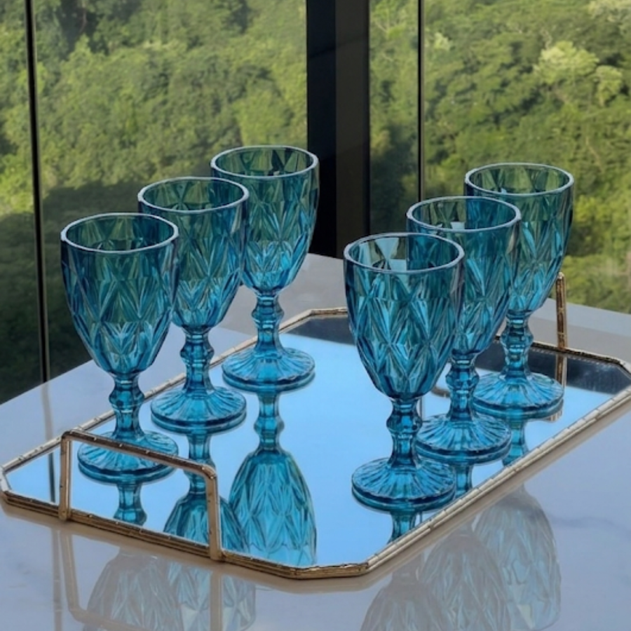 Taças de acrílico diamond azul sobre bandeja espelhada com vista para jardim