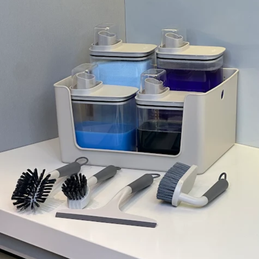 Kit lavanderia com dispensers e escovas organizados sobre bancada branca