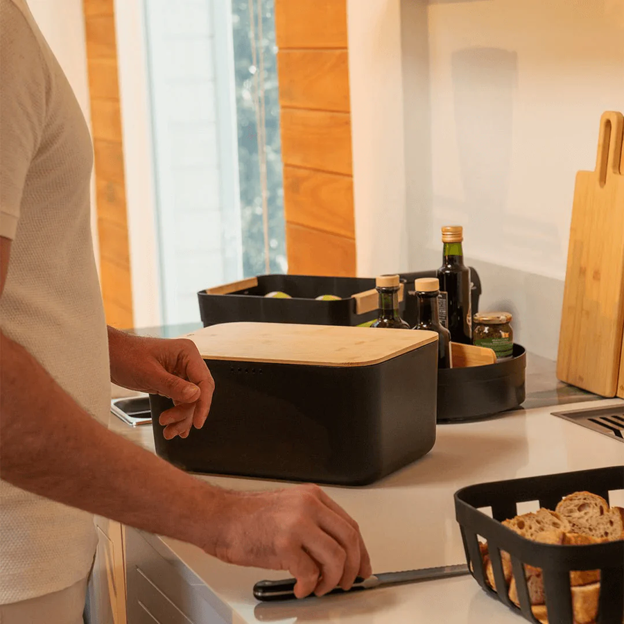 Homem usando porta pao preto com tampa de bambu na cozinha