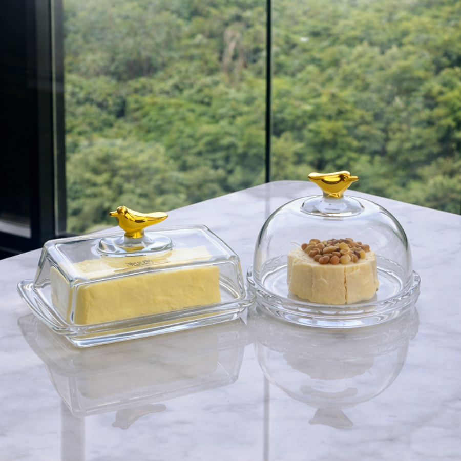 Manteigueira e queijeira Golden Bird em cristal com tampas de vidro e finais dourados sobre mesa