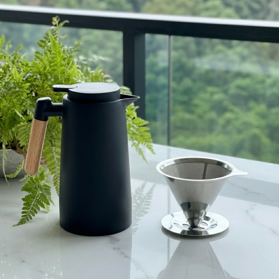 Jarra térmica preta com filtro de café sobre bancada de mármore