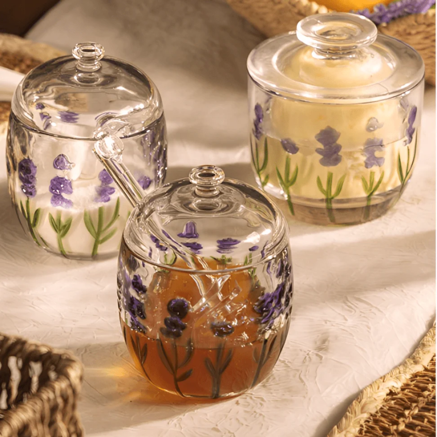 Potes de vidro com mel e acucar decorados com lavanda sobre mesa posta
