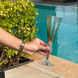 Mão segurando taça verde na beira da piscina