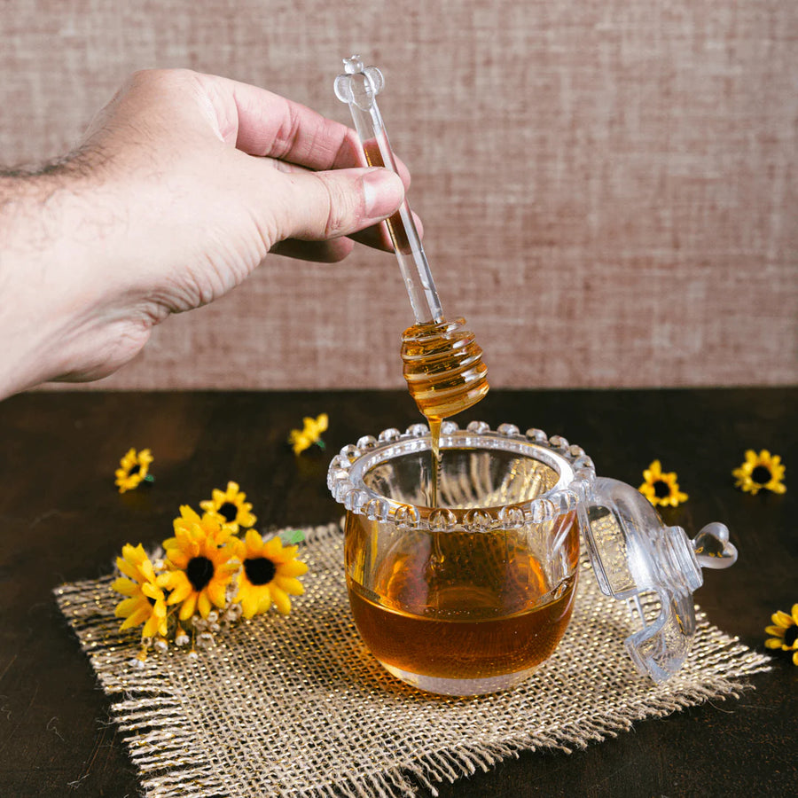 Colher de mel cristal vertendo sobre açucareiro com flores amarelas