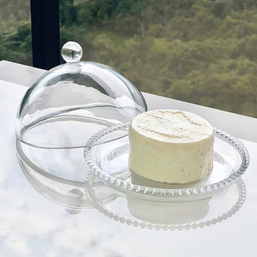 Boleira de cristal aberta com queijo e detalhe da borda com bolinhas